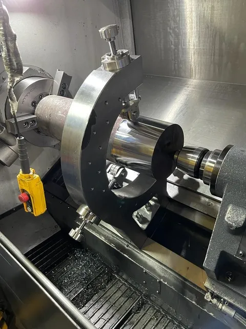 Corps de vérin hydraulique en cours d’usinage sur un tour CNC, soutenu par une lunette